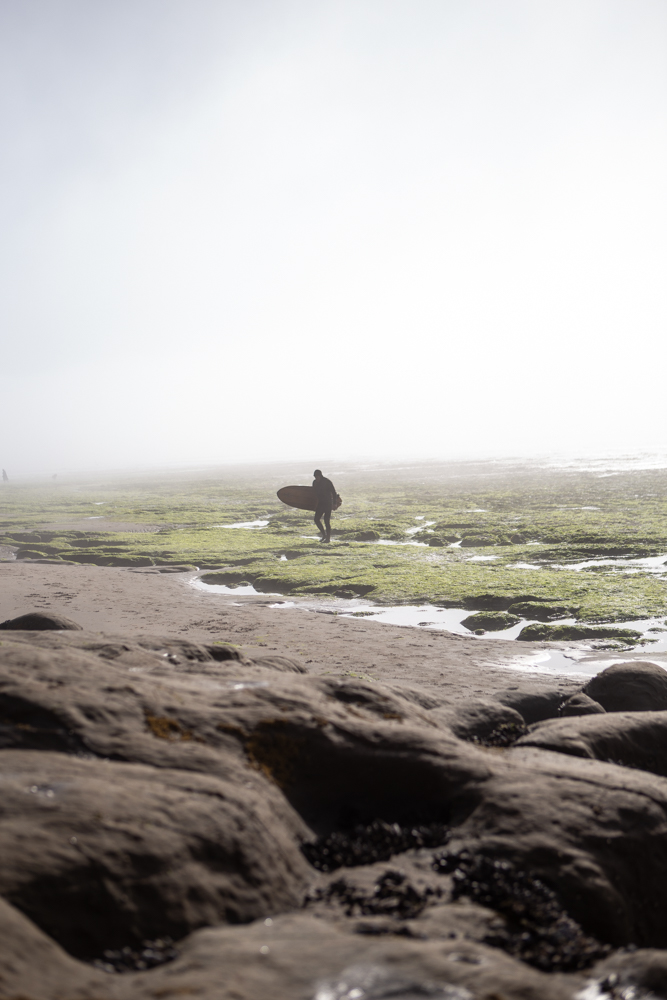 surfer wading through tide pools in pleasure point, Santa Cruz ca